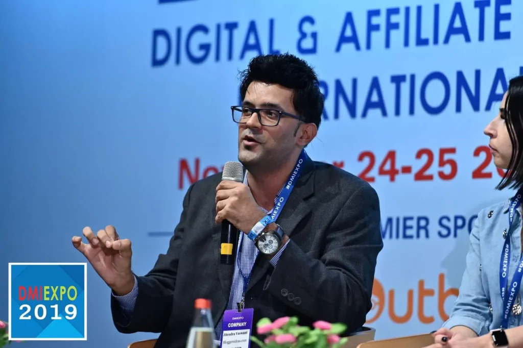 Jitendra Vaswani speaking with a microphone at a digital and affiliate marketing conference