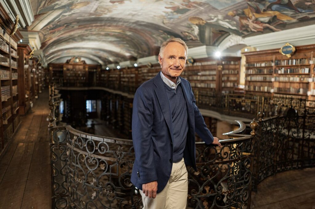 Dan Brown in the Baroque Library Hall of the Klementinum in Prague during a book tour visit, part of the Langdon story behind Dan Brown net worth